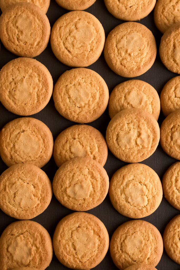 Close-up of crispy wafer cookies with chocolate and vanilla cream layers on a wooden table.