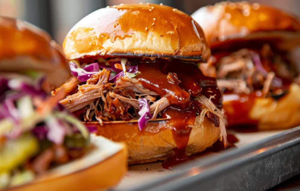 Close-up of a smoked brisket sandwich with creamy mustard sauce and fresh toppings.