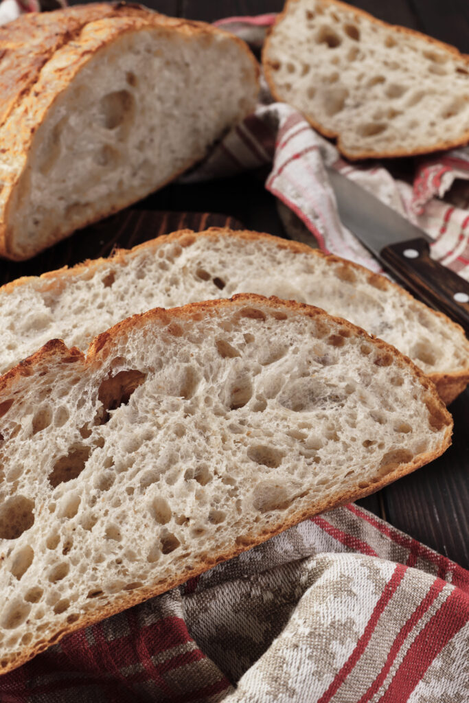 Freshly baked artisan Italian bread with a golden crust on a rustic wooden table.