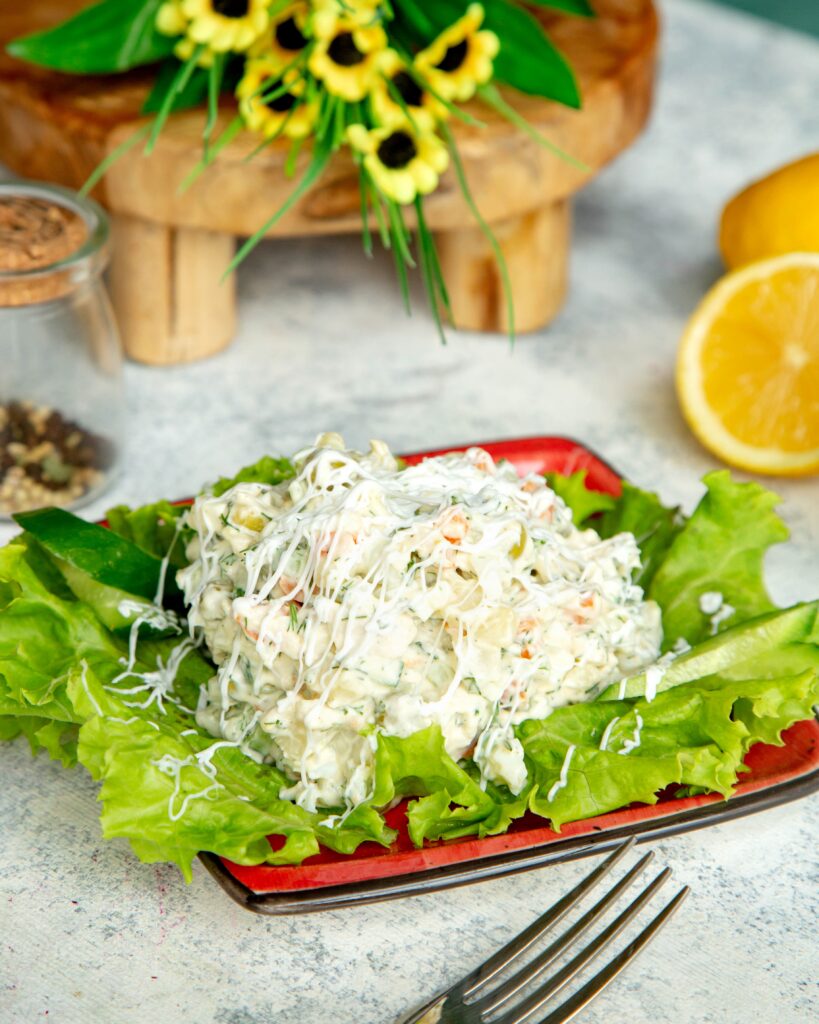 A bowl of creamy Chicken Salad Chick recipe garnished with fresh herbs and served with crackers on the side.