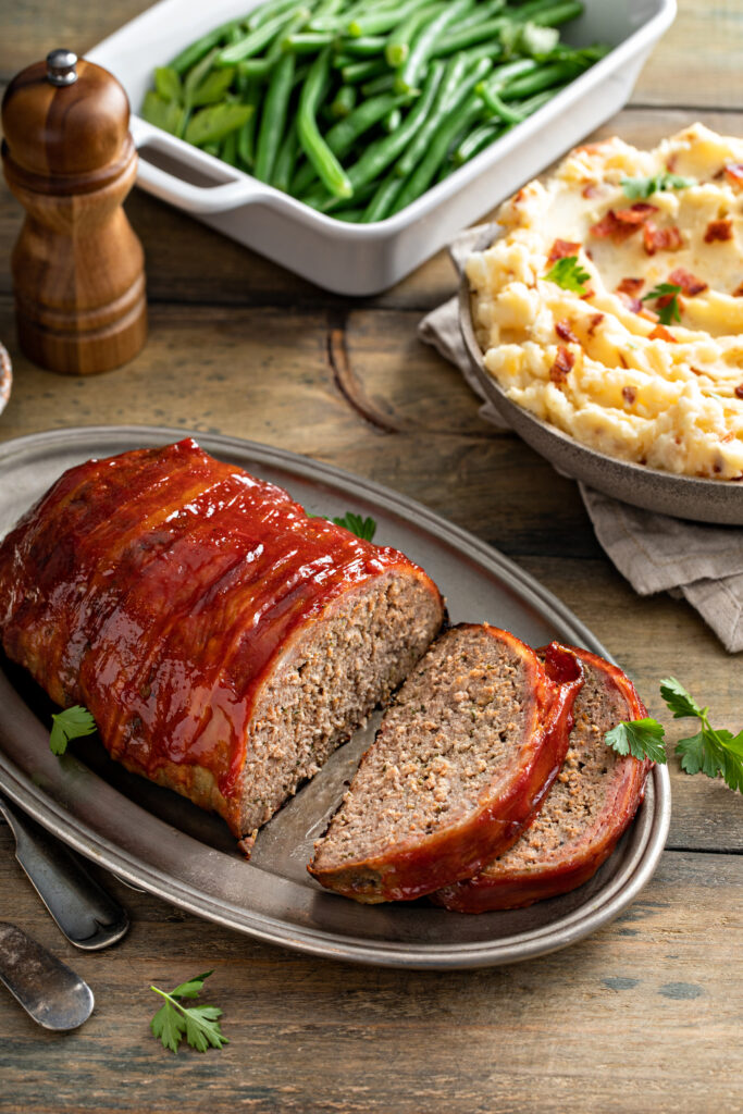 A beautifully plated smoked meatloaf with creamy mashed potatoes and roasted vegetables, showcasing the perfect dinner pairing.