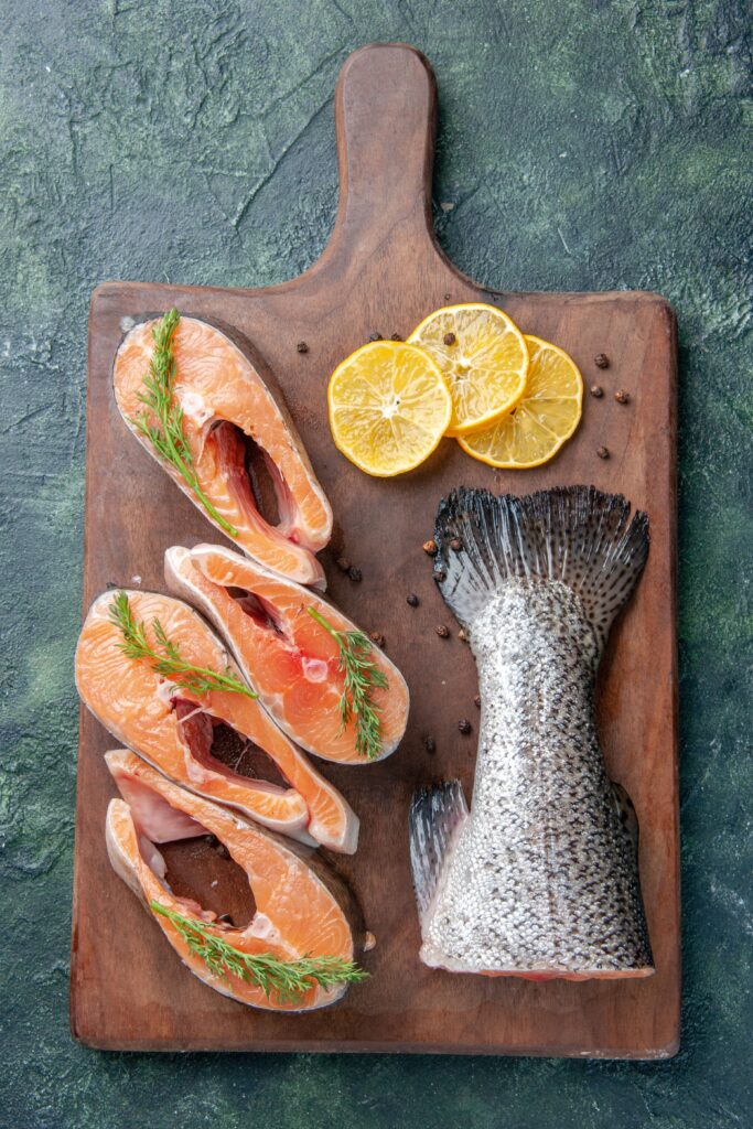 Freshly caught pink salmon on a rustic wooden board with a knife and seasonings.